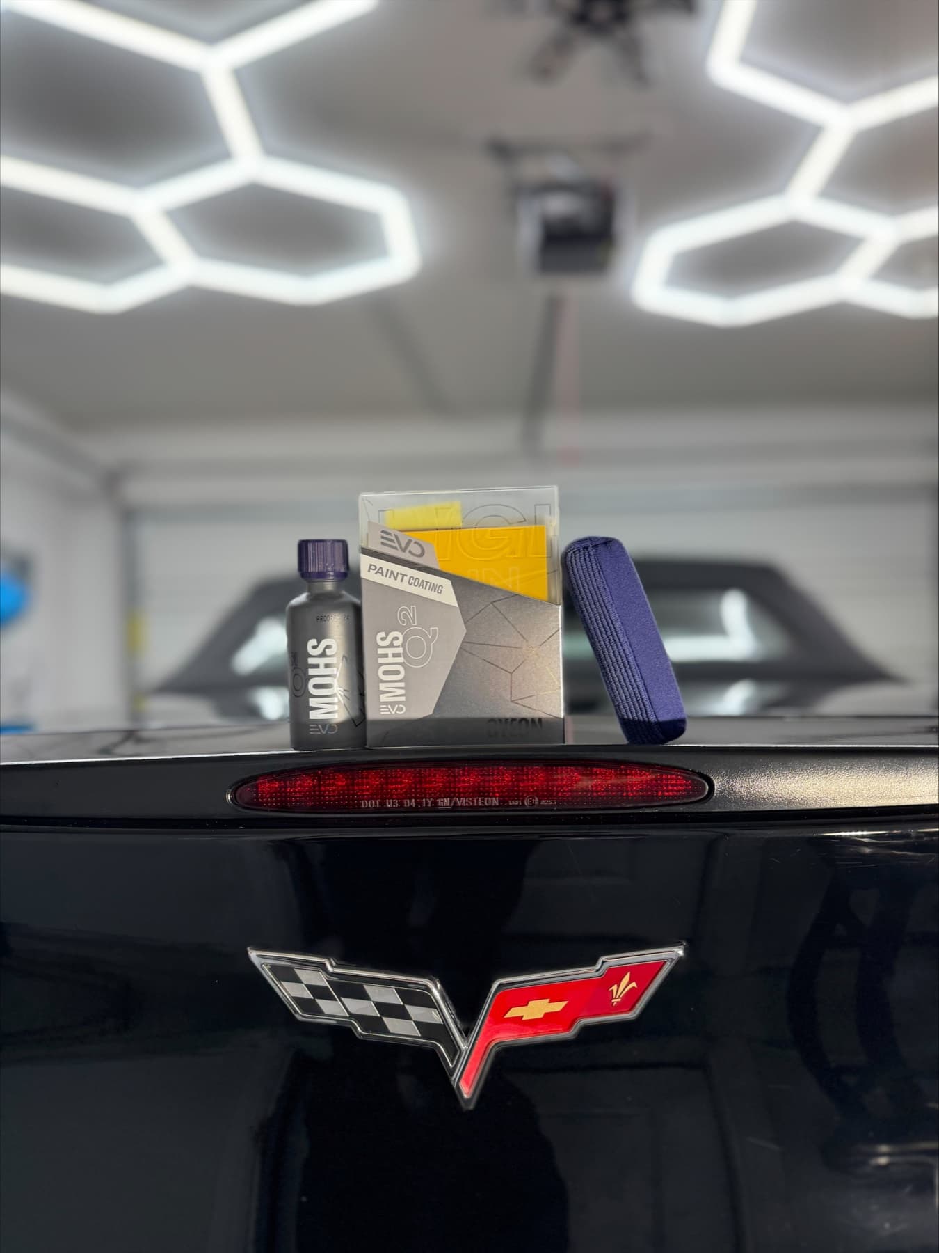 Ceramic paint-coating products displayed on a detailed Corvette